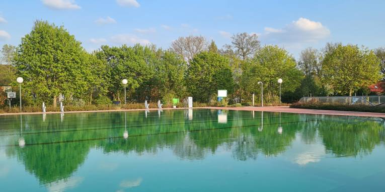 Schwimmbecken eines Freibades mit Wasser gefüllt, ohne Menschen, an einem sonnigen Tag